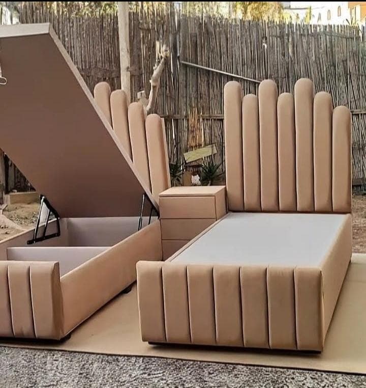 Pair of single beds with fluted headboards and lift-up storage bases, one shown open.