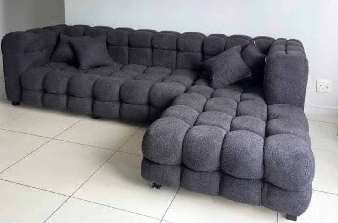 Charcoal cube-tufted sectional couch with a soft pillowed surface and scatter cushions.