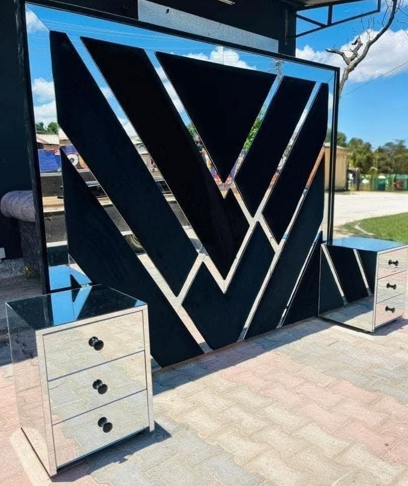 Headboard with a mirrored chevron pattern over black velvet, with two mirrored pedestals.