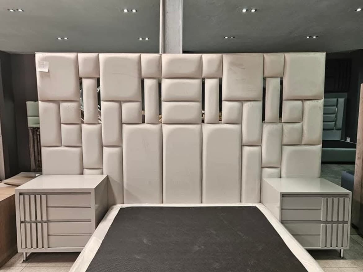 Headboard built from offset cream upholstered blocks, with a matching pedestal on each side.