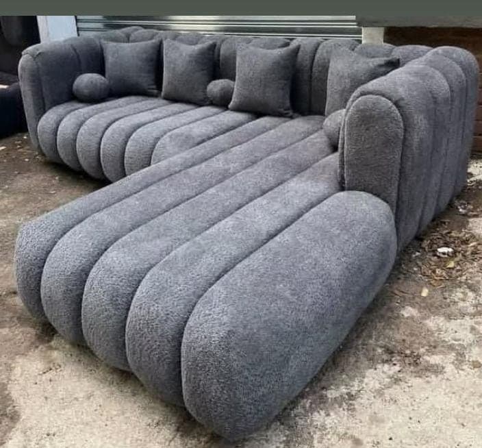 L-shaped grey bouclé sectional with deep channelled seating and scatter cushions.